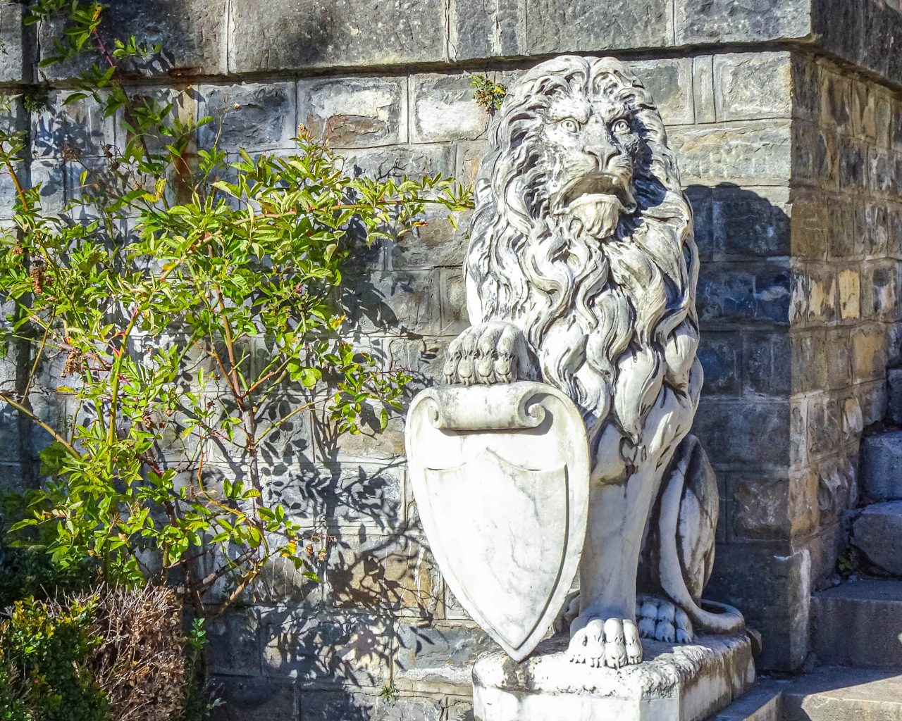 Standbeeld-van-leeuw-met-schild-in-tuin-Peles
