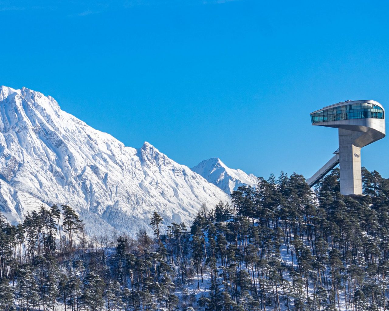 Bergisel-schans-in-Innsbruck-met-blauwe-lucht-en-besneeuwde-bergen