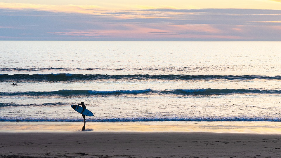 Surfer-met-board-tijdens-zonsondergang-strand-Portugal