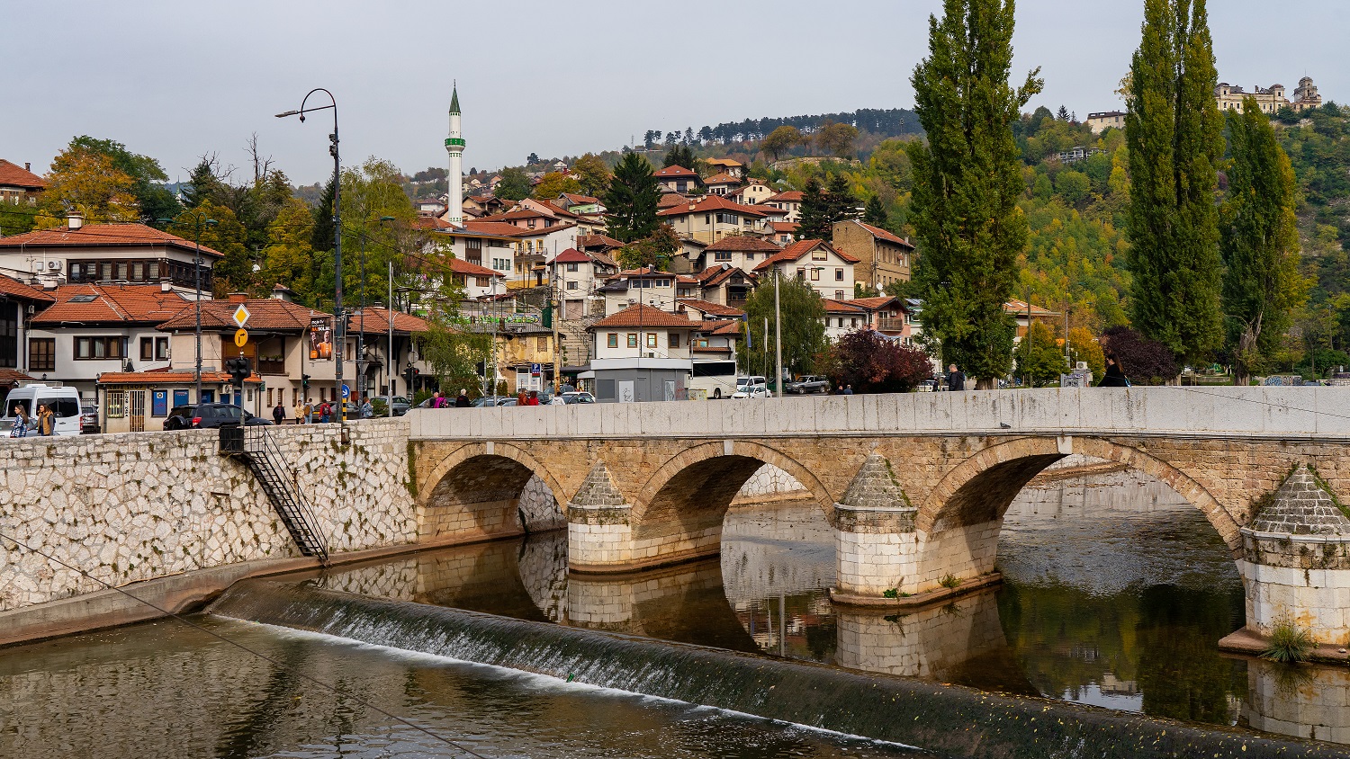 Rivier-met-brug-en-uitzicht-op-woonwijk-in-Sarajevo